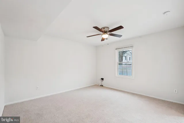 an empty room with a window and a ceiling fan