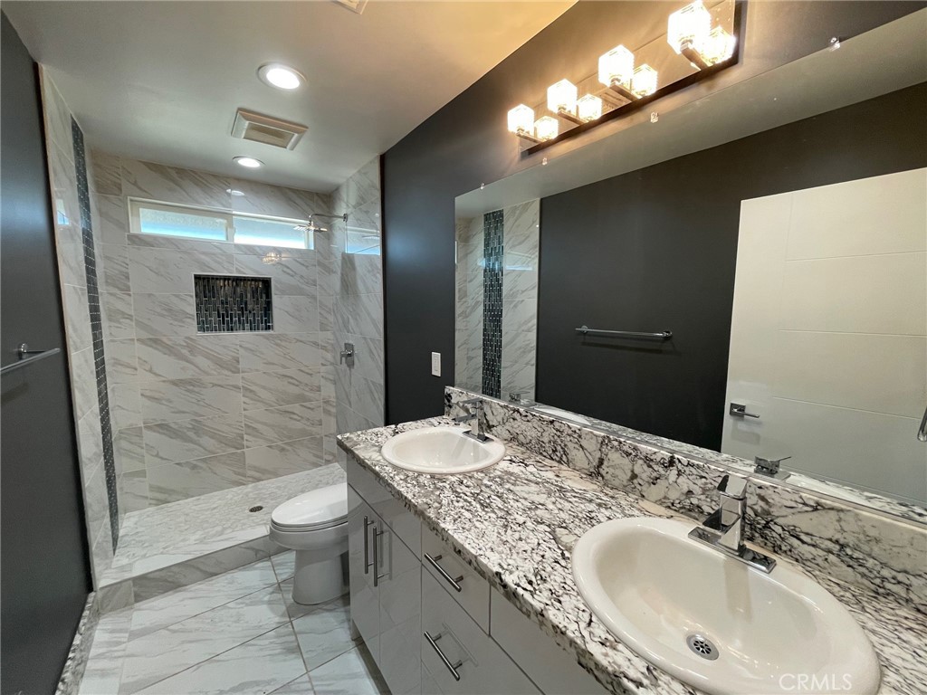10055 East Ave R 10 Littlerock, CA 93543 - Photo 26 of 31 a bathroom with a granite countertop sink a toilet a mirror and shower