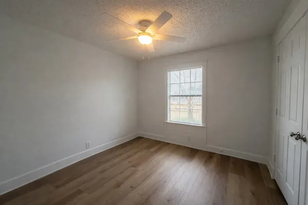 an empty room with wooden floor and windows