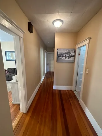 a view of a hallway with wooden floor and staircase