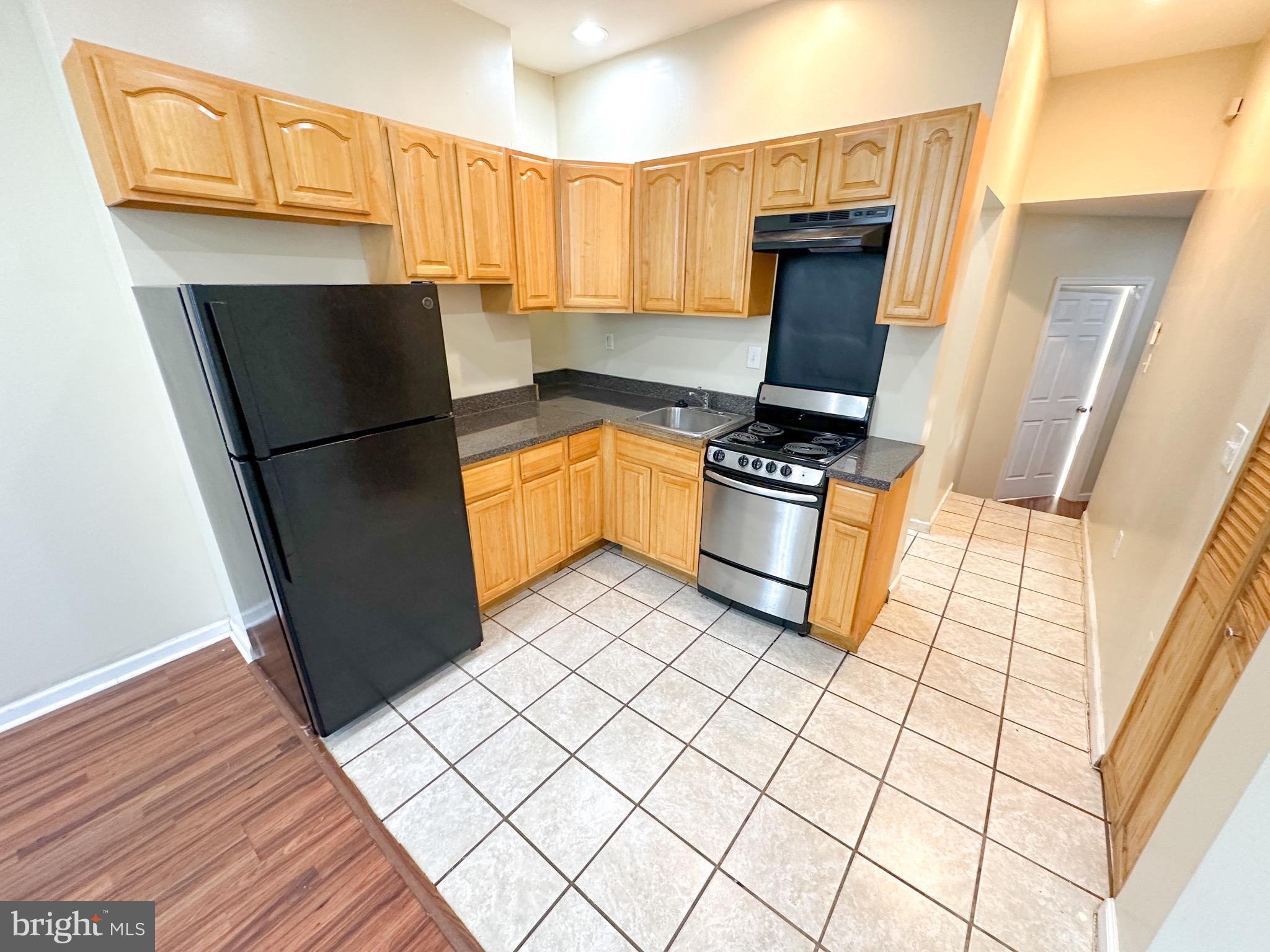 a kitchen with granite countertop a refrigerator and a stove top oven