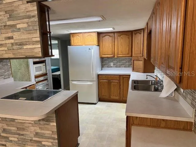 a kitchen with stainless steel appliances granite countertop a refrigerator a stove and a sink with wooden cabinets