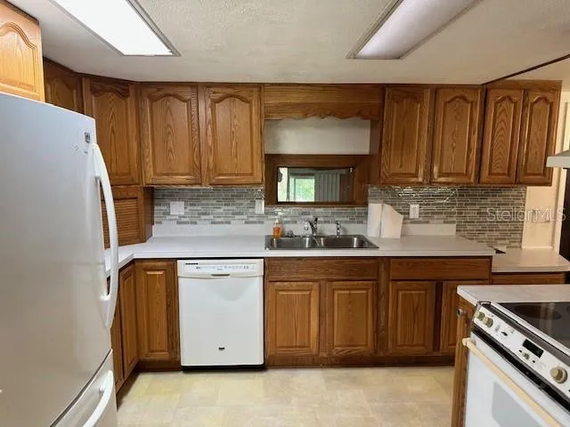 a kitchen with granite countertop a refrigerator stove and sink