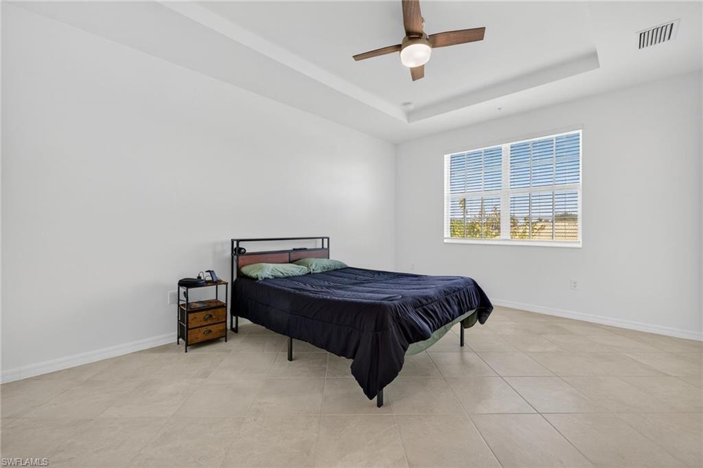 12041 Santaluz Drive, Unit 202 Fort Myers, FL 33913 - Photo 12 of 42 Primary Bedroom featuring ceiling fan, a tray ceiling, and light tile patterned floors
