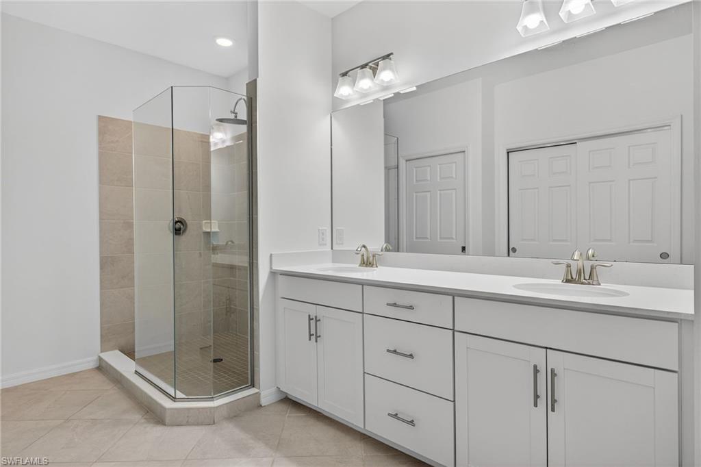 12041 Santaluz Drive, Unit 202 Fort Myers, FL 33913 - Photo 15 of 42 En Suite bathroom featuring double vanity, a stall shower, light tile patterned flooring, and recessed lighting