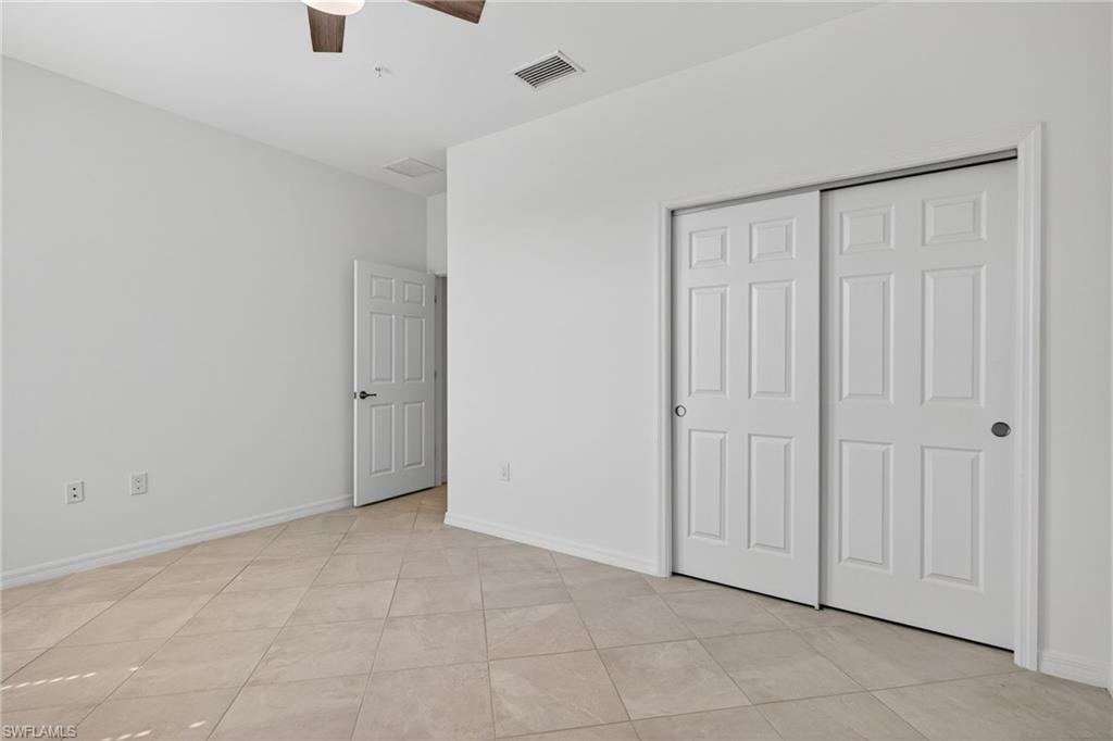 12041 Santaluz Drive, Unit 202 Fort Myers, FL 33913 - Photo 17 of 42 Unfurnished bedroom featuring ceiling fan, light tile patterned flooring, and a closet
