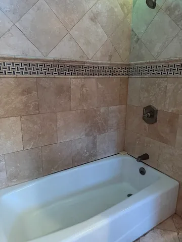 a bath tub sitting next to a white sink and shower