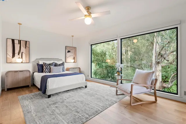 a spacious bedroom with a bed a chair and a large window