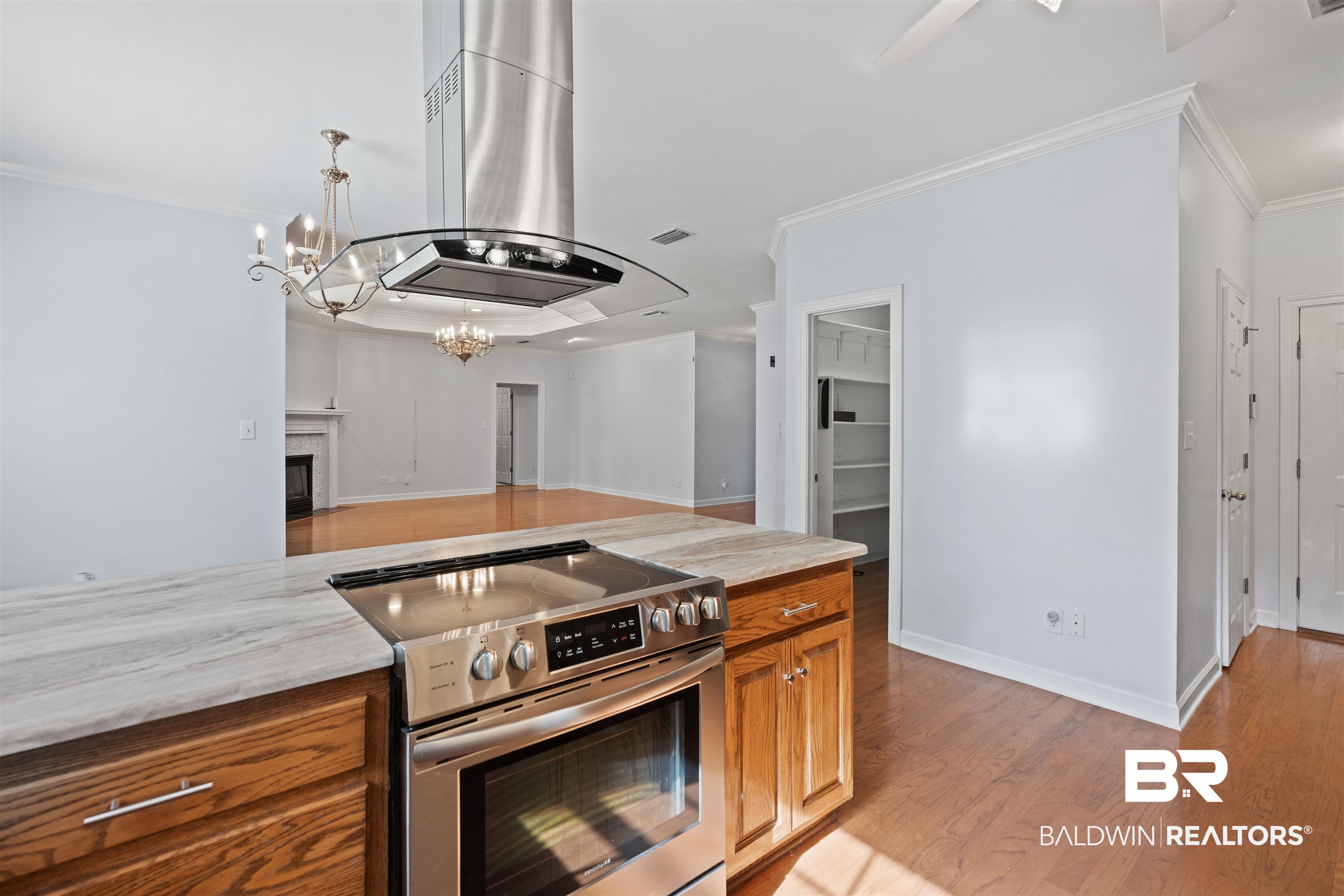 4 Judd Trail Daphne, AL 36527 - Photo 12 of 45 Kitchen featuring brown cabinets, island exhaust hood, stainless steel electric range, light wood finished floors, and a chandelier
