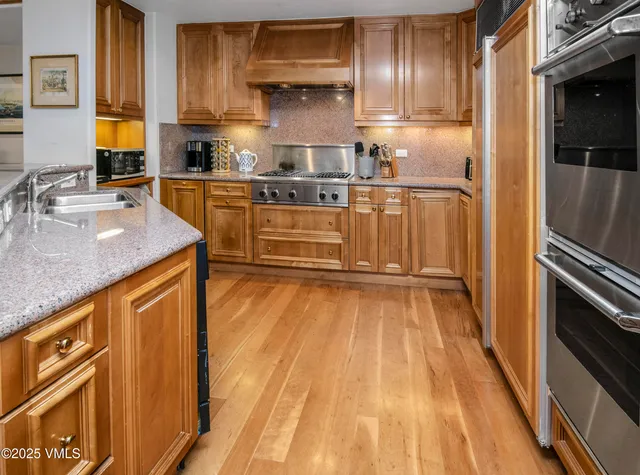 a kitchen with stainless steel appliances granite countertop a sink a stove and cabinets