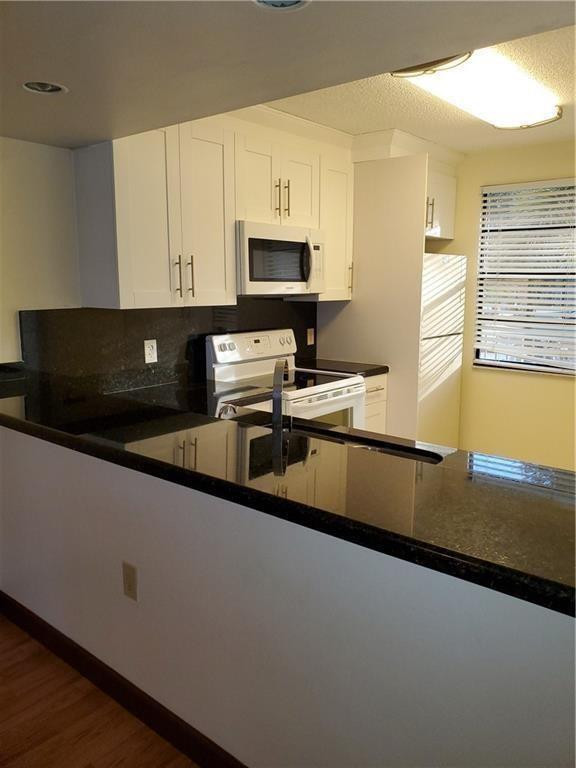 6061 Balboa Circle, Unit 201 Boca Raton, FL 33433 - Photo 4 of 7 a kitchen with stainless steel appliances a sink a stove and white cabinets