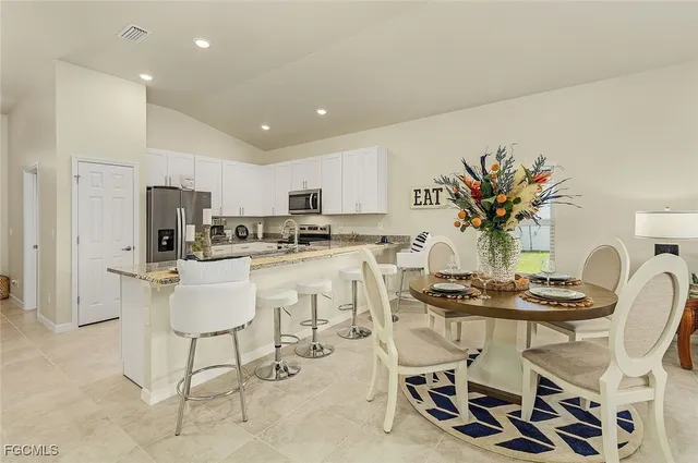 a dining room with furniture a potted plant and kitchen view