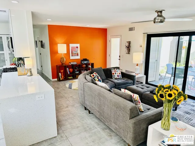 a living room with furniture and a flat screen tv with kitchen view