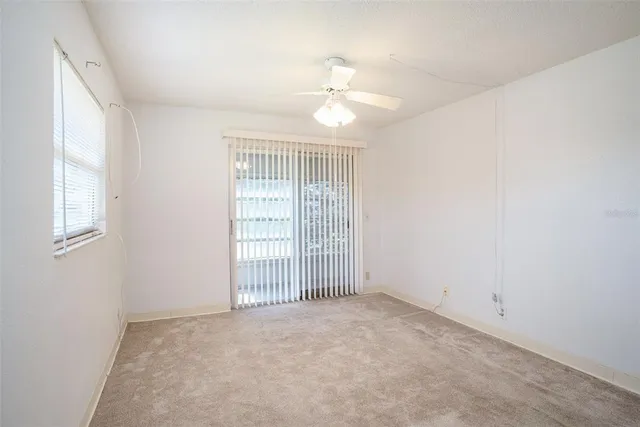an empty room with windows and chandelier fan