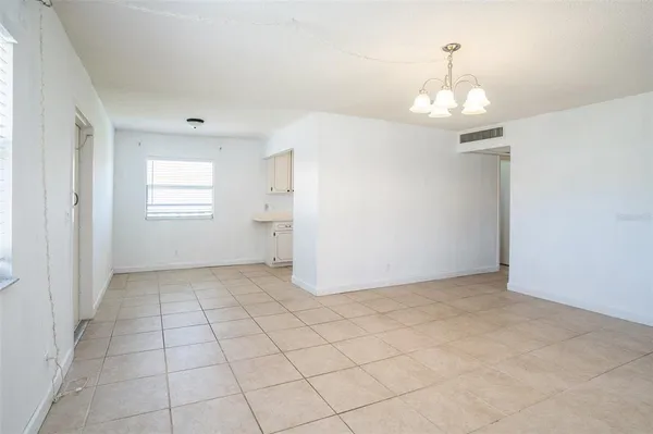 an empty room with kitchen chandelier and windows