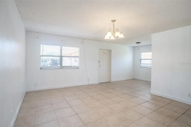 an empty room with chandelier fan and windows