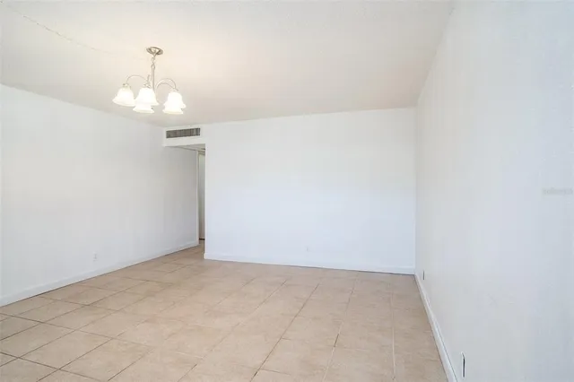 an empty room with a chandelier fan and windows