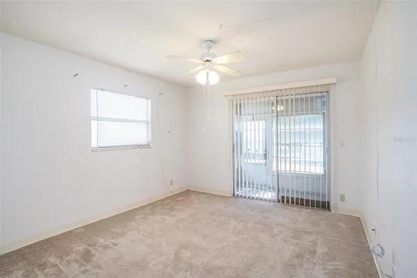 an empty room with a window and a fan