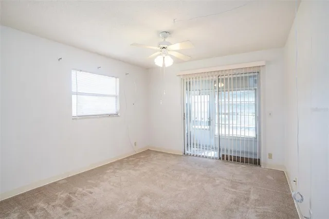 an empty room with a window and a fan