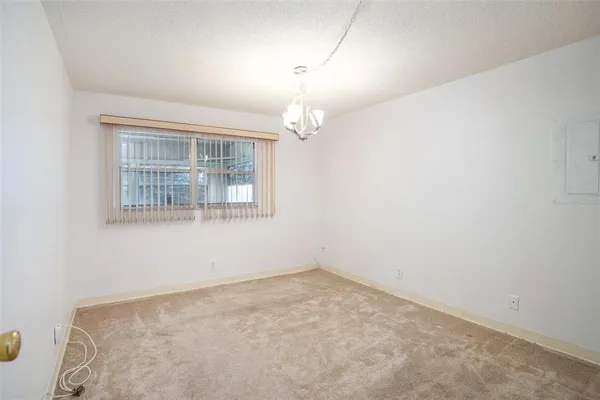 an empty room with chandelier fan and windows