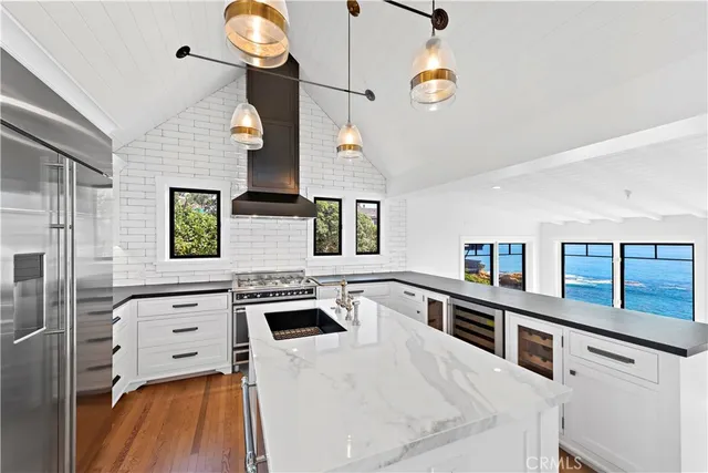 a kitchen with stainless steel appliances granite countertop a white cabinets a stove top oven a sink and a window