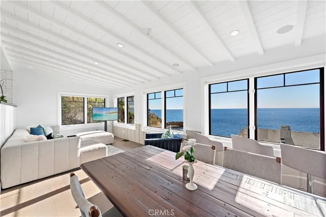 a living room with furniture large windows and wooden floor