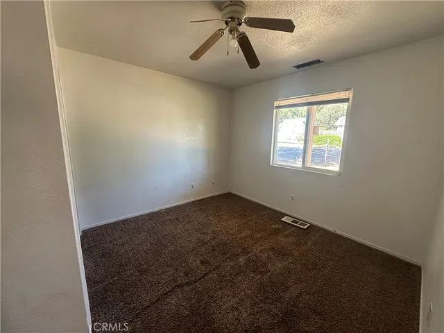 an empty room with windows and fan