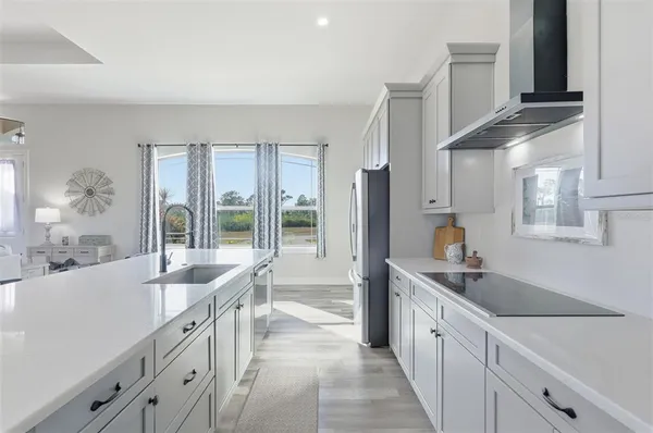 a large kitchen with stainless steel appliances wooden floor a large window and a sink