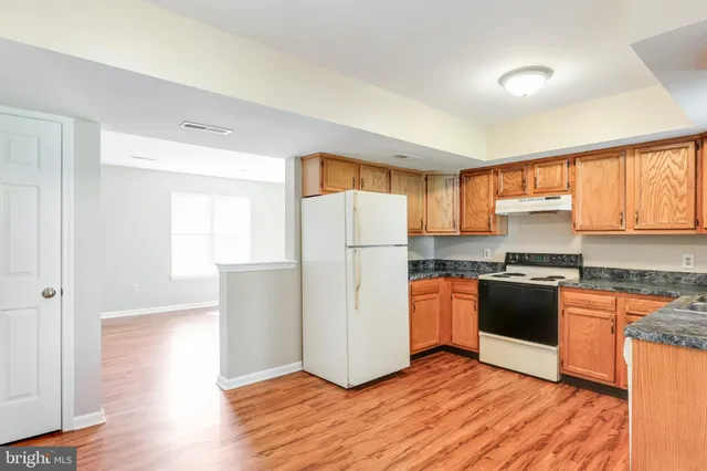 a kitchen with granite countertop a refrigerator stove top oven and sink