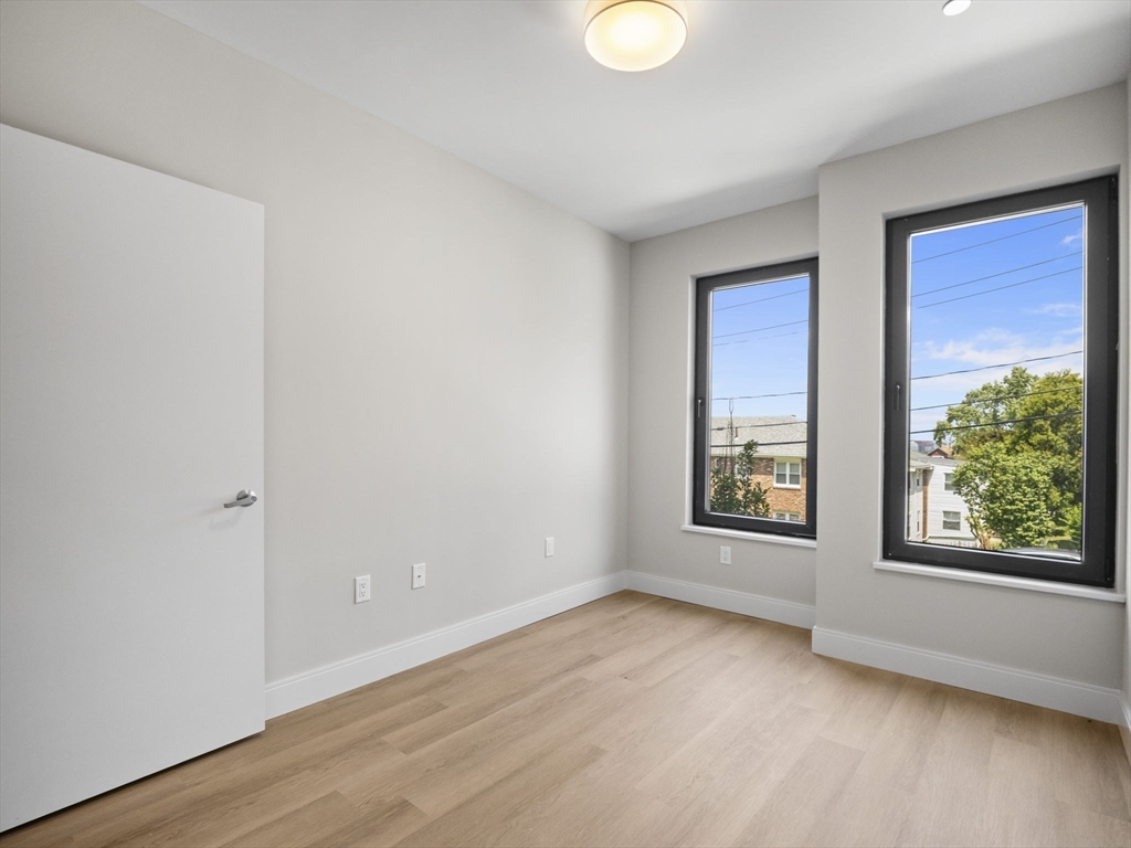 249 Corey Road, Unit 105 Boston, MA 02135 - Photo 15 of 39 an empty room with wooden floor and windows
