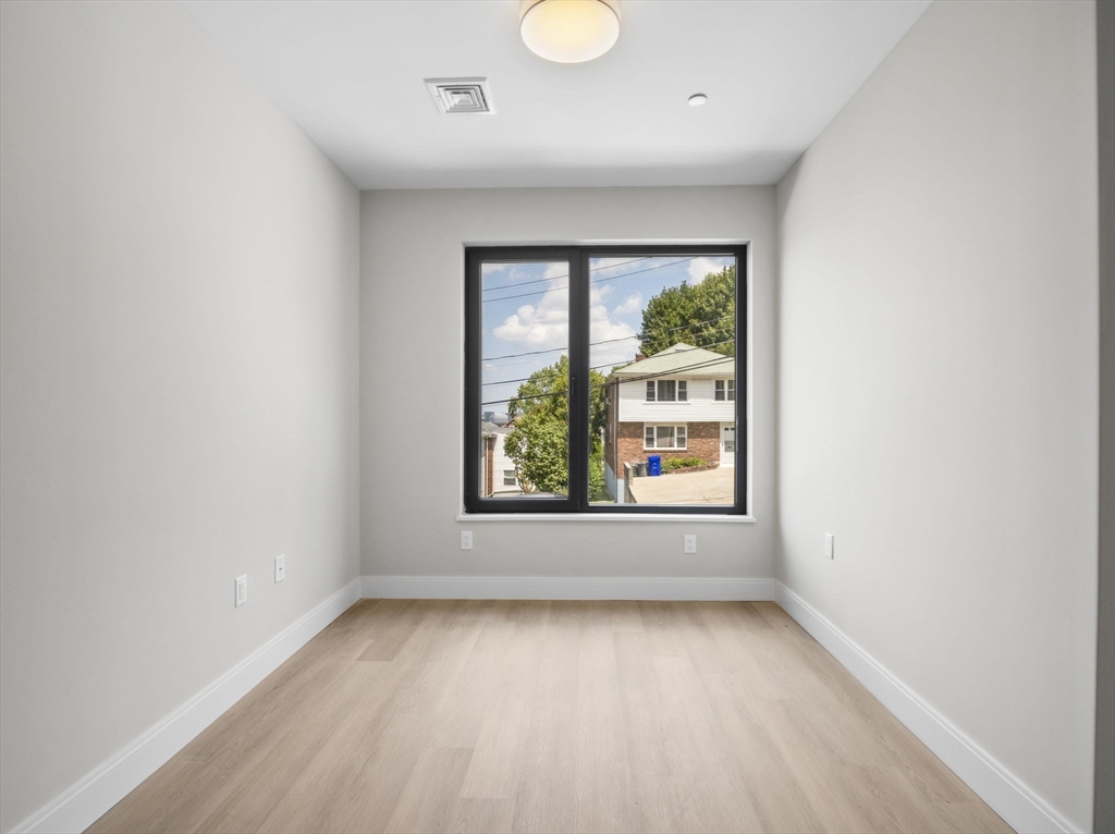 249 Corey Road, Unit 105 Boston, MA 02135 - Photo 25 of 39 an empty room with wooden floor and windows