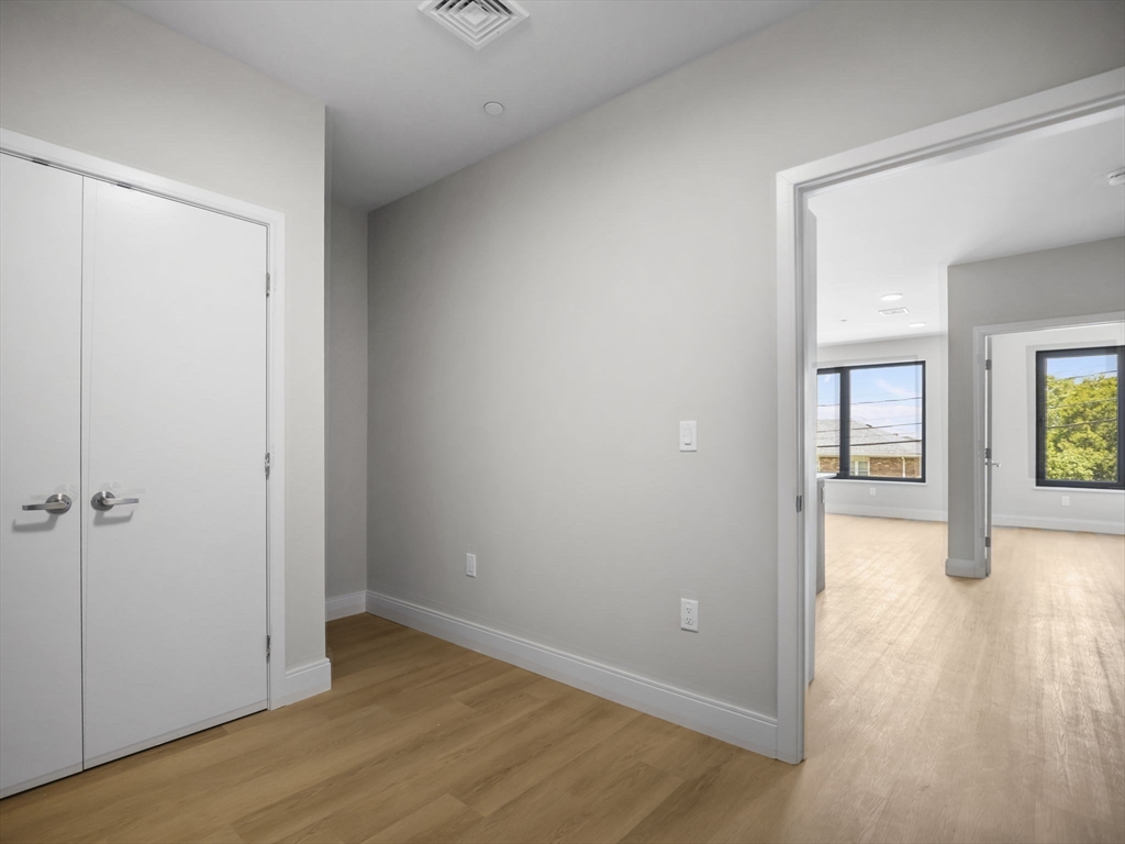 249 Corey Road, Unit 105 Boston, MA 02135 - Photo 9 of 39 an empty room with wooden floor and windows