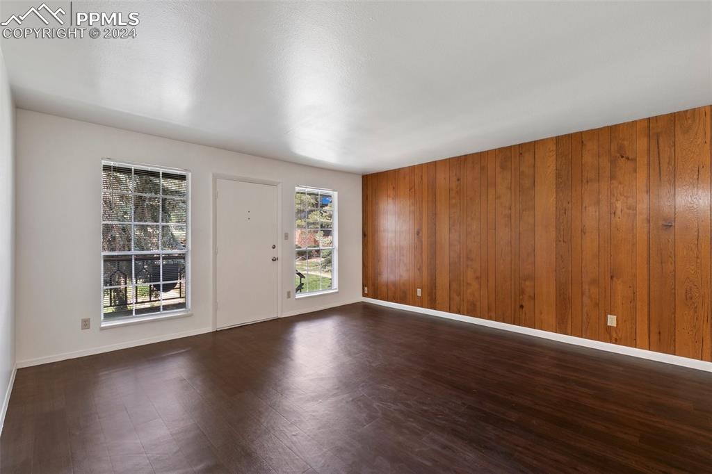 2902 Airport Road, Unit 215 Colorado Springs, CO 80910 - Photo 14 of 17 an empty room with wooden floor and windows with curtains
