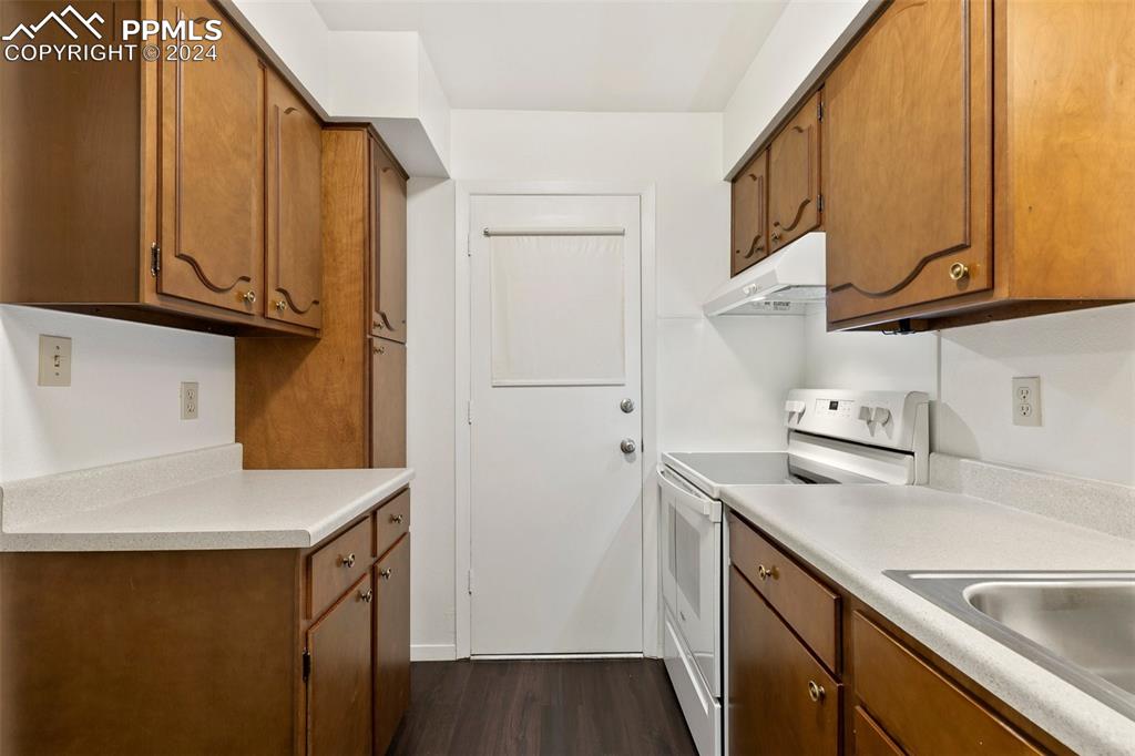 2902 Airport Road, Unit 215 Colorado Springs, CO 80910 - Photo 7 of 17 a kitchen with stainless steel appliances a sink a stove and a refrigerator with wooden floor