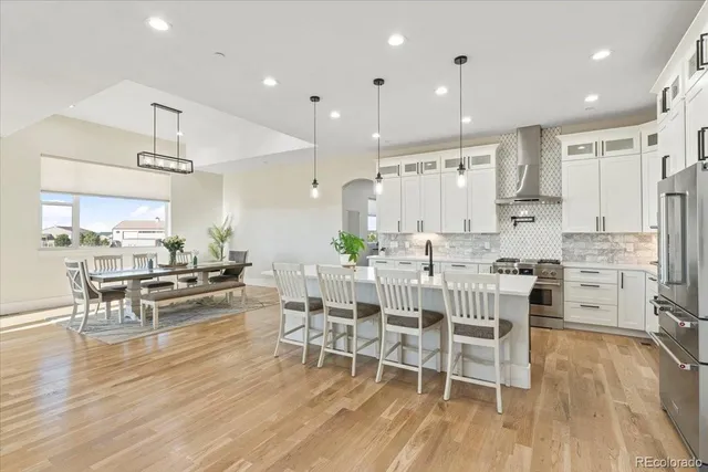 a kitchen with stainless steel appliances kitchen island granite countertop a stove a sink a dining table and chairs with wooden floor