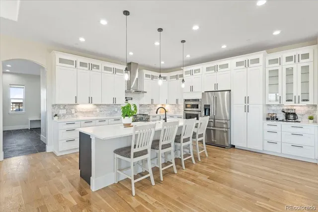 a kitchen with stainless steel appliances kitchen island granite countertop a wooden floor and white cabinets