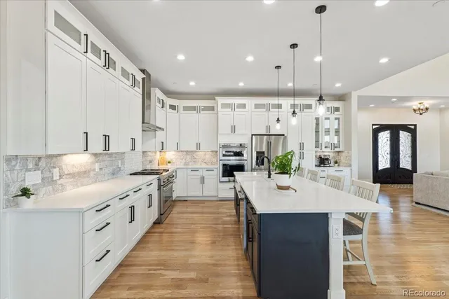 a large white kitchen with lots of counter space wooden floor and appliances