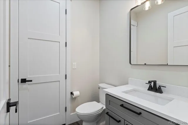 a bathroom with a granite countertop toilet sink and mirror