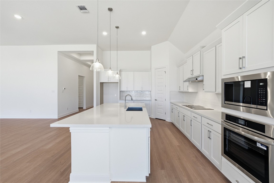 1208 Terrace View Drive Georgetown, TX 78628 - Photo 4 of 15 a kitchen with stainless steel appliances kitchen island granite countertop a stove a sink and white cabinets with wooden floor