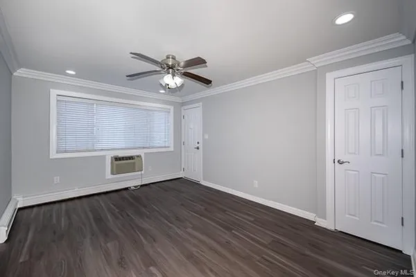 a view of an empty room with a window and wooden floor