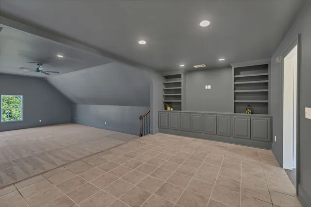 an empty room with a ceiling fan and window