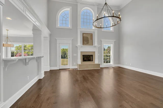 an empty room with wooden floor white walls and windows