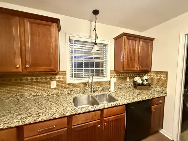 a kitchen with granite countertop cabinets sink and window