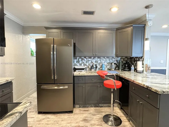 a kitchen with kitchen island granite countertop a sink cabinets and refrigerator