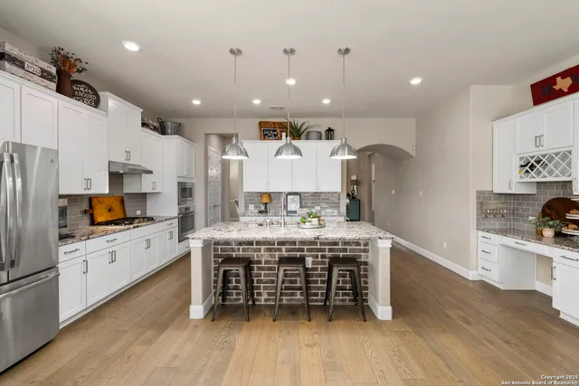 a kitchen with stainless steel appliances granite countertop a stove refrigerator and a wooden cabinets
