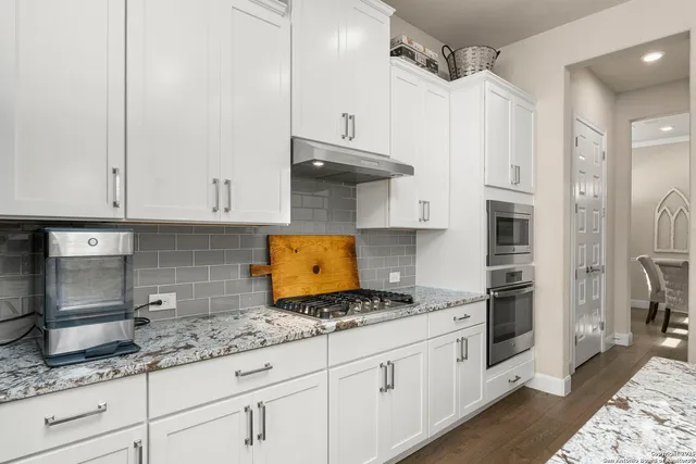 a kitchen with granite countertop a sink stainless steel appliances and cabinets