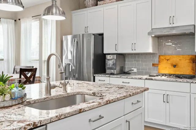 a kitchen with granite countertop a sink stainless steel appliances and white cabinets