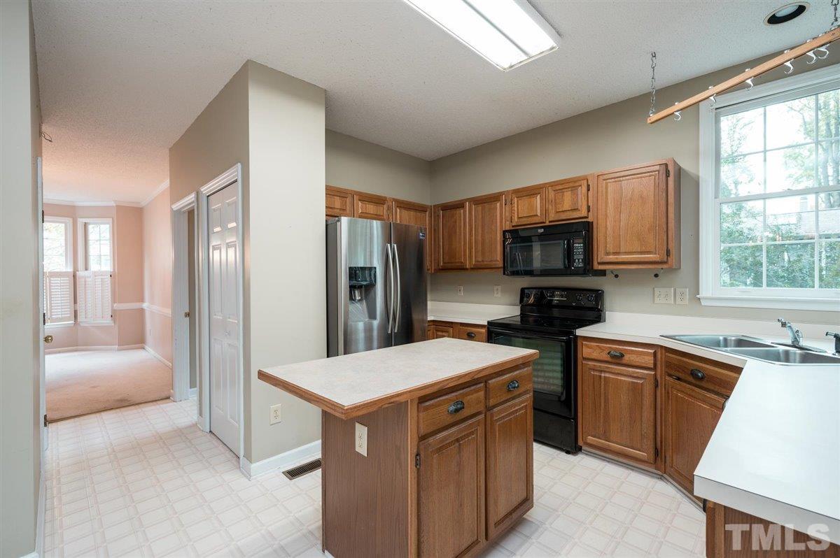 5617 Barham Court Raleigh, NC 27613 - Photo 17 of 30 a kitchen with a sink refrigerator and microwave