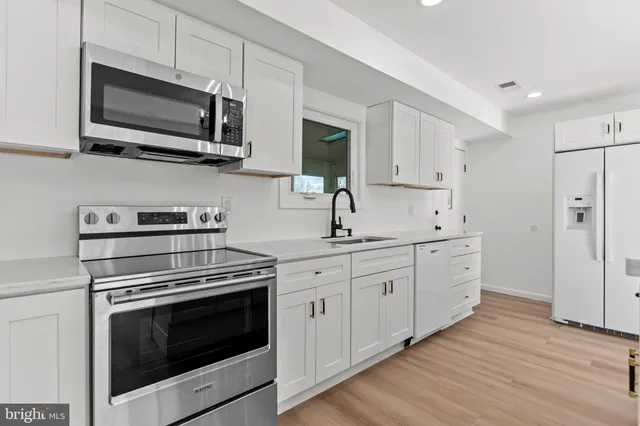 a kitchen with stainless steel appliances a white cabinet and a stove top oven