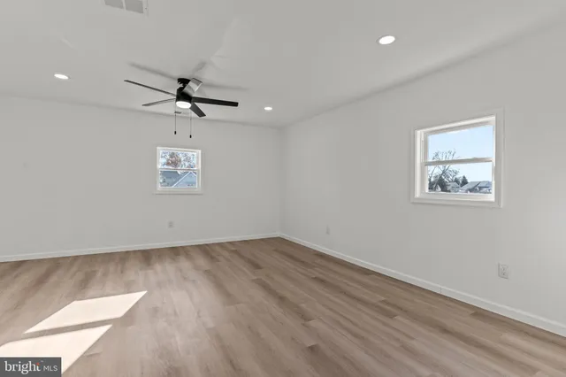 an empty room with a ceiling fan and wooden floor